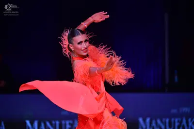 Dancesport competitor: Female dancer: orange Latin dress with feather trim on the sleeves and shoulders