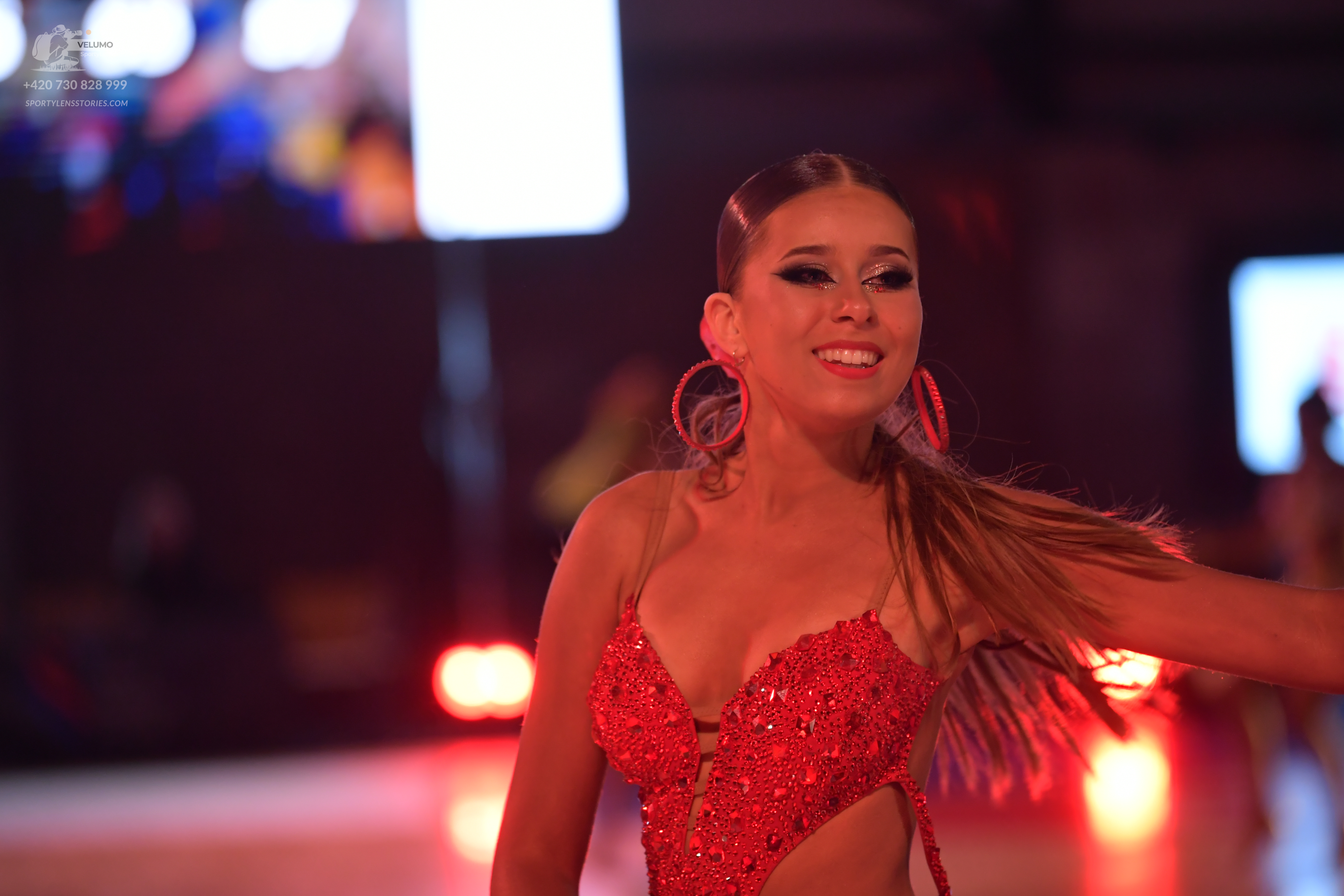 Dancesport competitor: Female dancer: red sequin latin dress with fringe and large red hoop earrings
