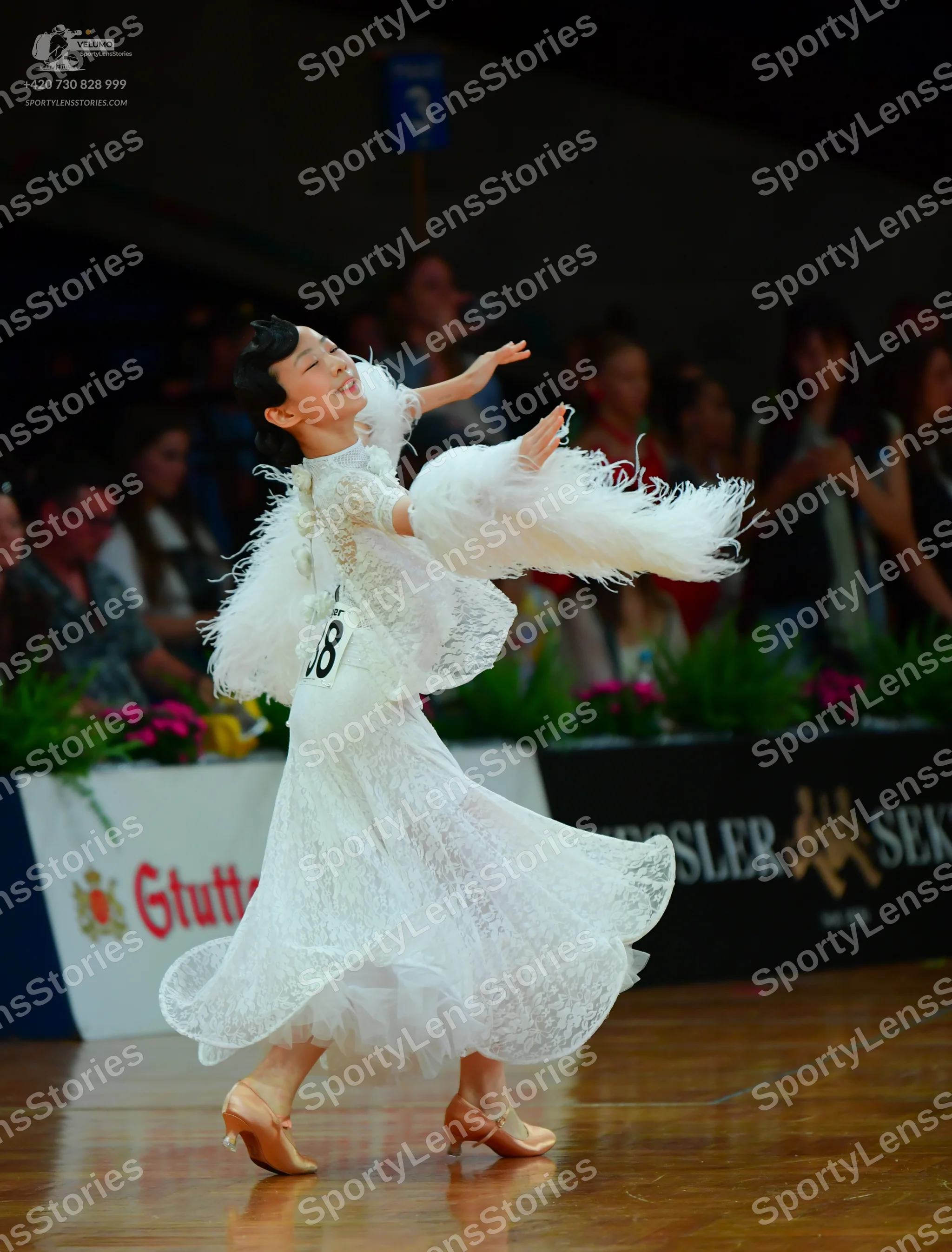 Dancesport competitor: Female dancer: white lace ballgown with large white feathery sleeves