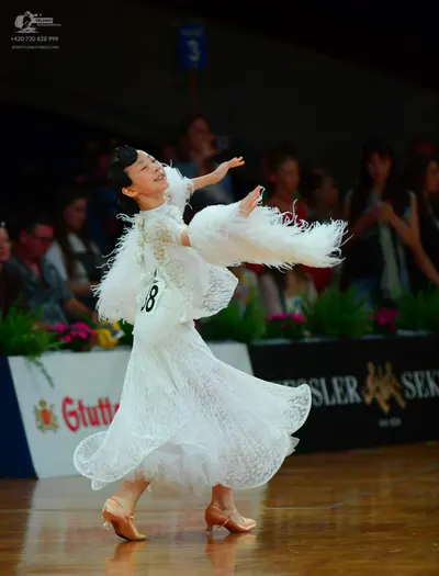 Dancesport competitor: Female dancer: white lace ballgown with large white feathery sleeves