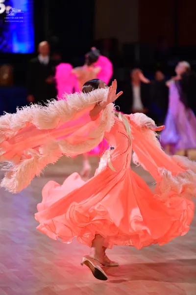 Dancesport competitor: Main female dancer: peach ballroom dress with a large, voluminous ruffled skirt 