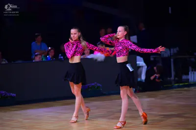 Dancesport competitor: Female dancers: matching long-sleeved tops with a pink and black pattern, black 