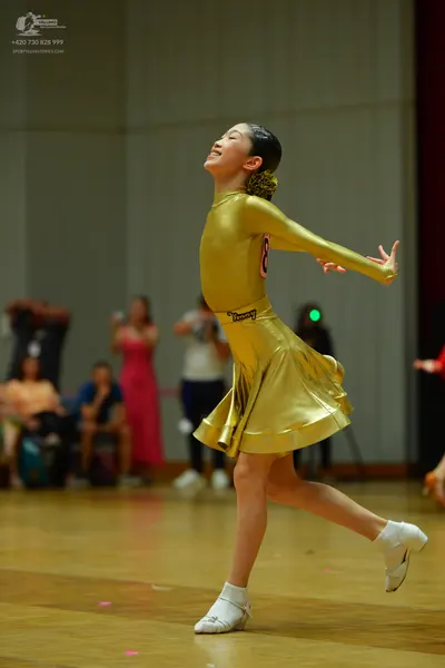 Dancesport competitor: Female dancer: shiny gold, long-sleeved, metallic latin dance dress with a flare