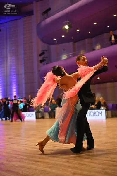 Dancesport competitor: Female dancer: light blue flowy dress with large pink feather-like accents