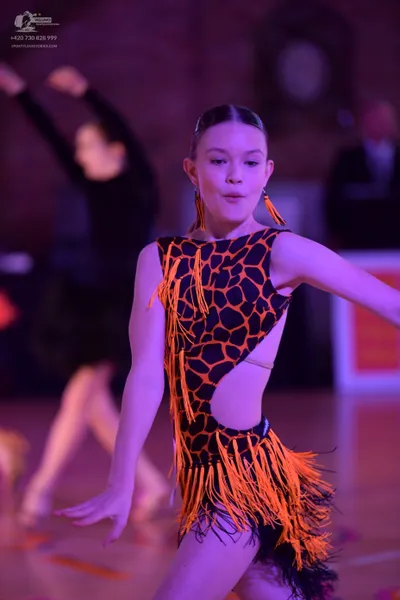 Dancesport competitor: Female dancer in foreground: black and orange animal print latin dress with long