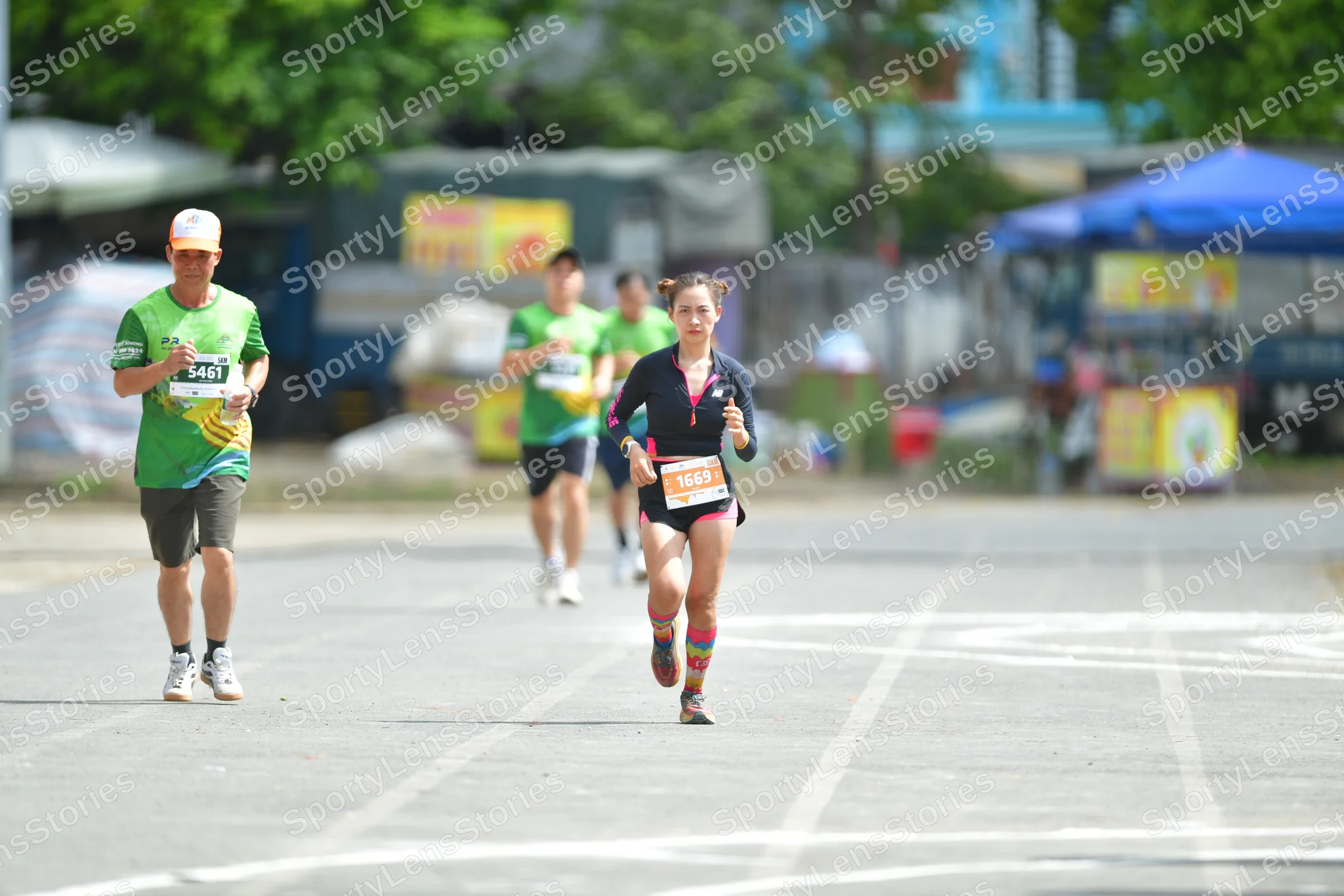 Marathon runner #5461, #5365: Runner 1: green jersey, grey shorts, white shoes, orange cap