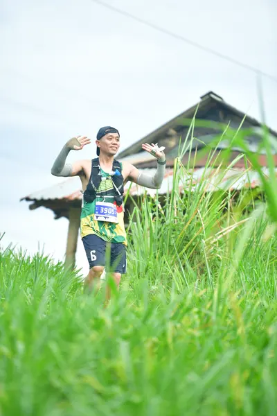 Marathon runner #3894: Runner 1: dark patterned tank top, dark shorts with a white number 6, and a dark