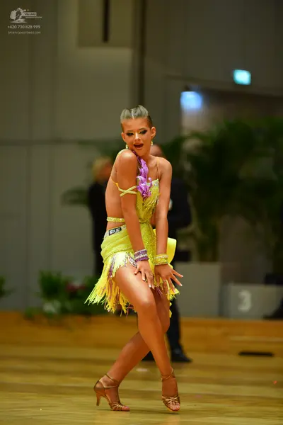 Dancesport competitor: Female dancer: yellow Latin dance dress with long fringe and matching yellow wri