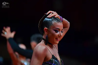Dancesport competitor: Female dancer: black latin-style dress with thin straps and sparkly, sequined em