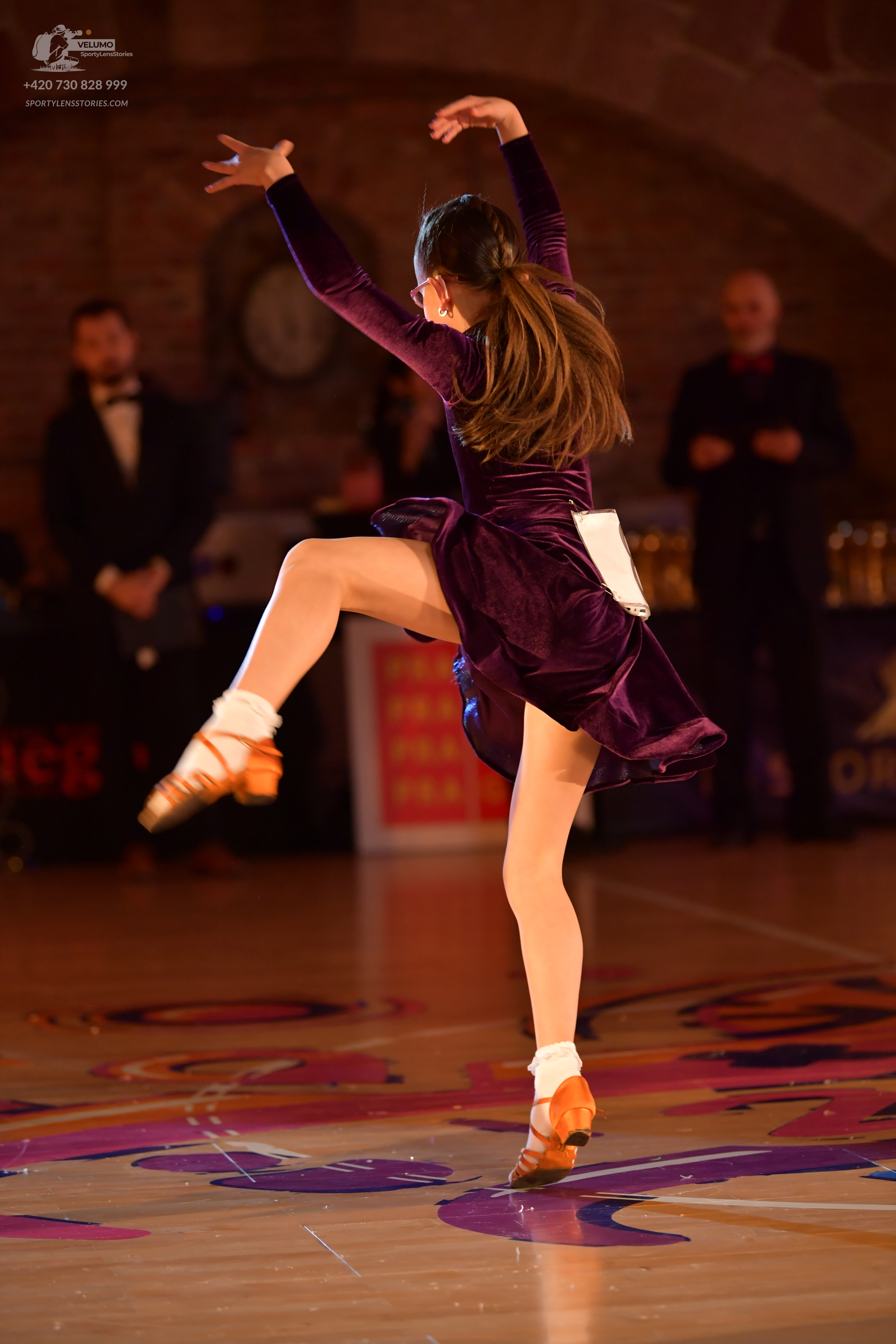 Dancesport competitor: Female dancer: dark purple velvet Latin dress with long sleeves