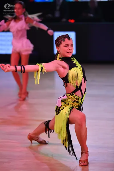 Dancesport competitor: Foreground dancer: black and lime green latin dress with long fringe and cutouts
