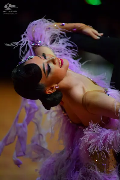 Dancesport competitor: Female dancer: light purple Latin dance dress featuring long lavender feathers, 