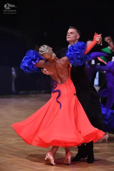 Dancesport competitor: Female dancer: red ballroom gown with a voluminous skirt, blue/purple sequin det