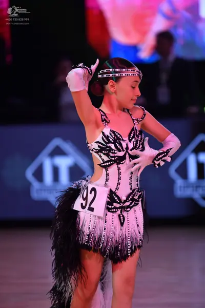 Dancesport competitor: Female dancer: white latin dress with black patterns and black fringe, and white
