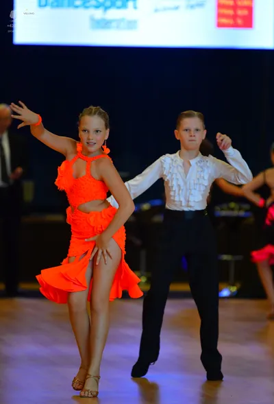 Dancesport competitor: Female dancer: bright orange Latin dance dress with a halter neck and a high sli
