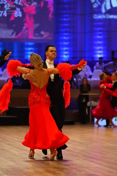 Dancesport competitor: Female dancer: red latin dress with sequin embellishments and large red feather-