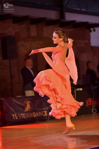 Dancesport competitor: Female dancer: peach-colored latin dress with long sleeves, a backless design, a