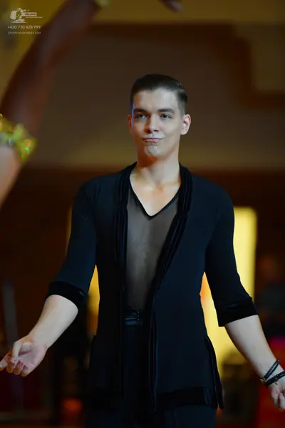 Dancesport competitor: Male dancer: black long-sleeved dance top with a deep V-neck, featuring a sheer 