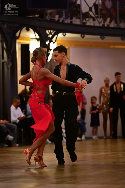 Dancesport competitor: Female dancer: red Latin dress with cutouts and nude-colored dance heels