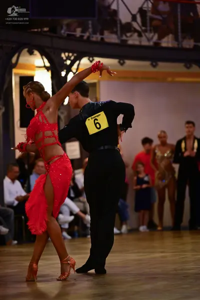 Dancesport competitor: Female dancer: red latin dress with sequins and mesh panels, matching red wristb