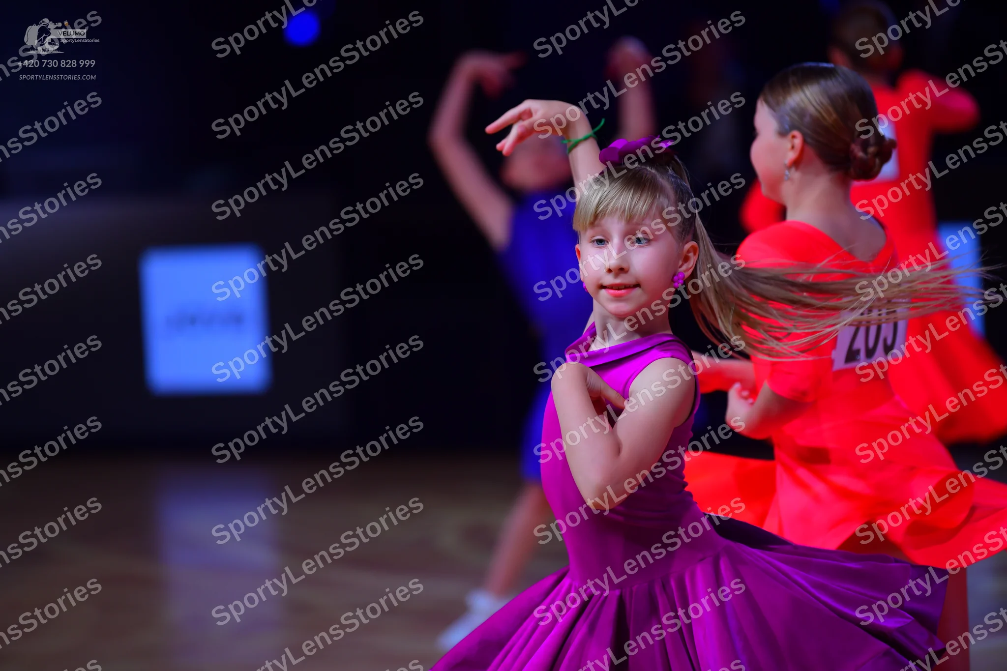 Dancesport competitor: Female dancer in foreground: magenta satin ballroom dress