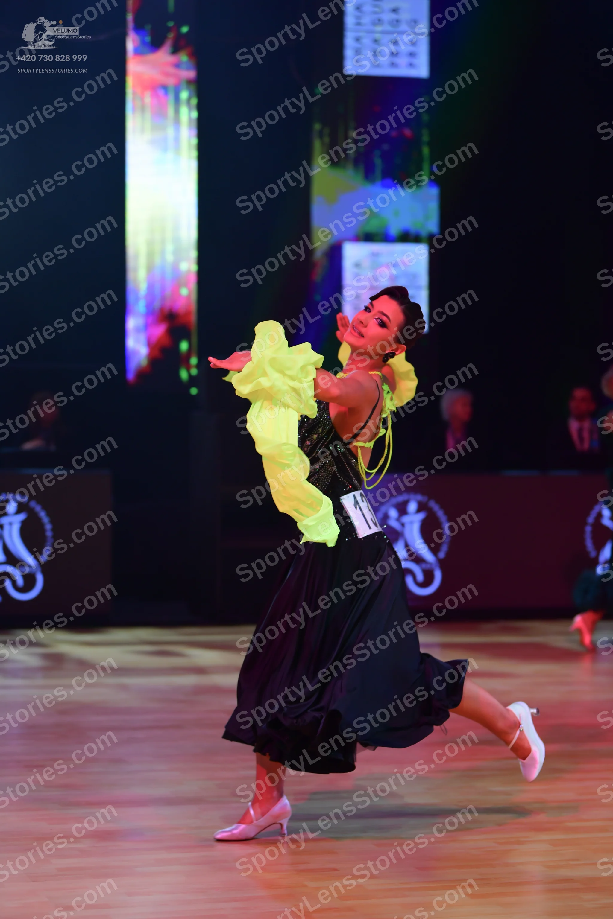 Dancesport competitor: Female dancer: black ballgown with a sequin bodice, large bright yellow ruffled 