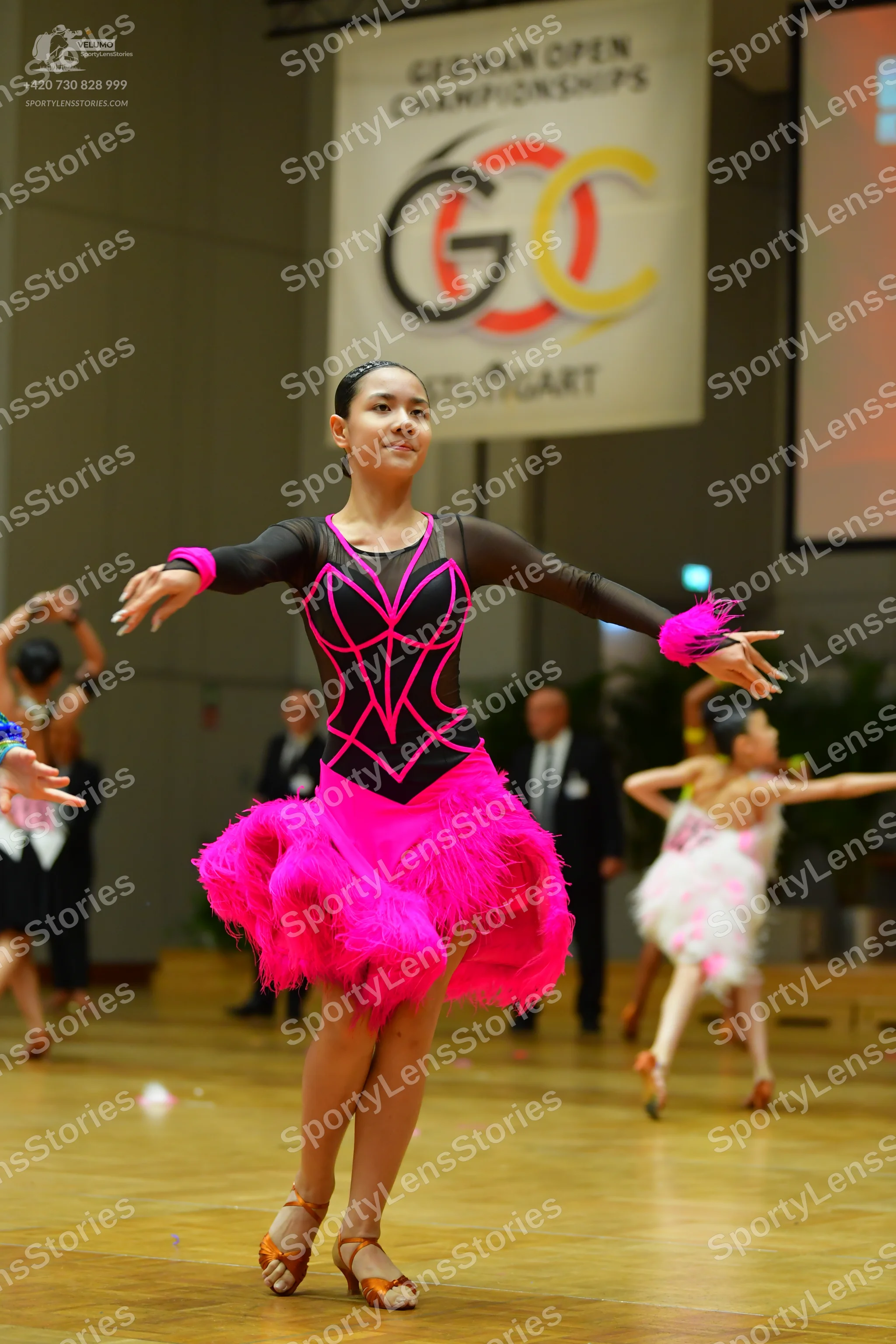 Dancesport competitor: Main female dancer: black long-sleeved Latin dress with a bright pink geometric