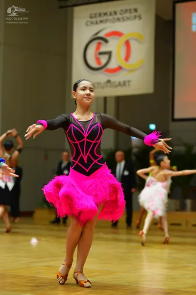 Dancesport competitor: Main female dancer: black long-sleeved Latin dress with a bright pink geometric 