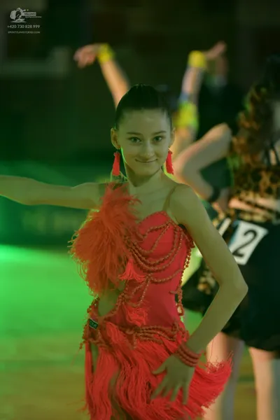 Dancesport competitor: Female dancer in foreground: coral pink Latin dress with heavy fringe
