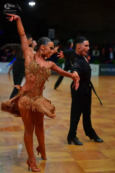 Dancesport competitor: Female dancer: bronze Latin dance dress with sequins and fringe