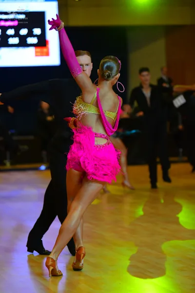 Dancesport competitor: Female dancer: bright pink Latin dance costume with gold sequin details on the b