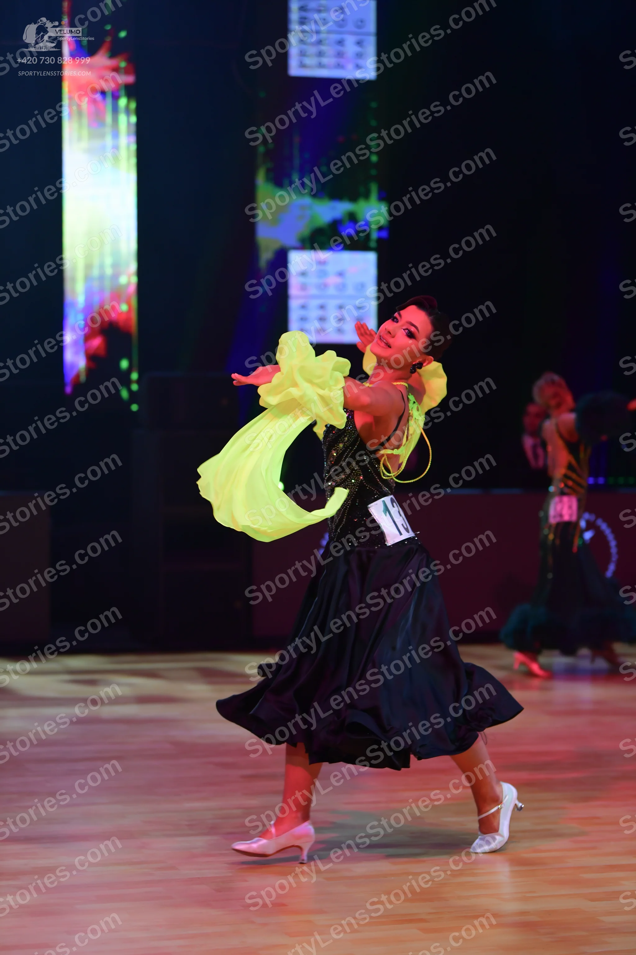 Dancesport competitor: Central dancer: black ballroom dress with voluminous neon yellow ruffled sleeves