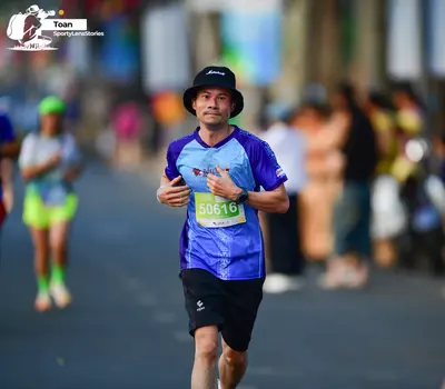 Marathon runner #50616: Runner 1: blue jersey, black shorts, black bucket hat, watch