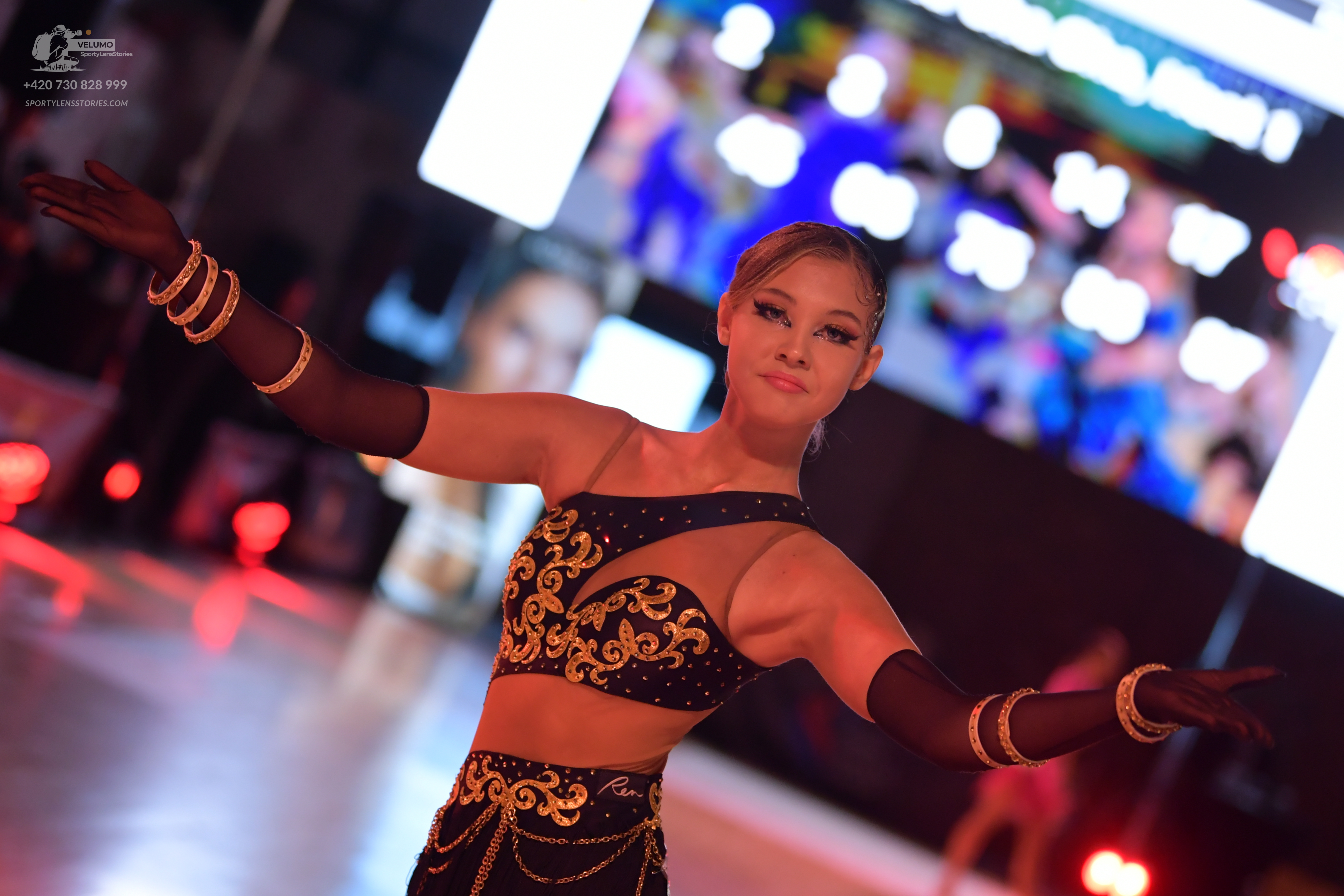 Dancesport competitor: Female dancer: black two-piece latin costume with gold sequin patterns and long 