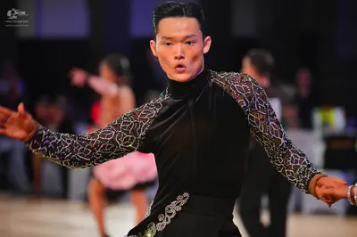 Dancesport competitor: Male dancer: black long-sleeved Latin dance top with sheer, patterned sleeves fe