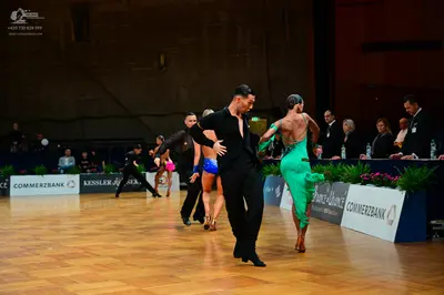 Dancesport competitor: Male dancer (foreground): black long-sleeved shirt and black trousers