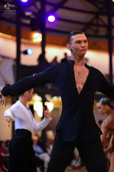 Dancesport competitor: Male dancer in foreground: black long-sleeved shirt with a textured or lace pane