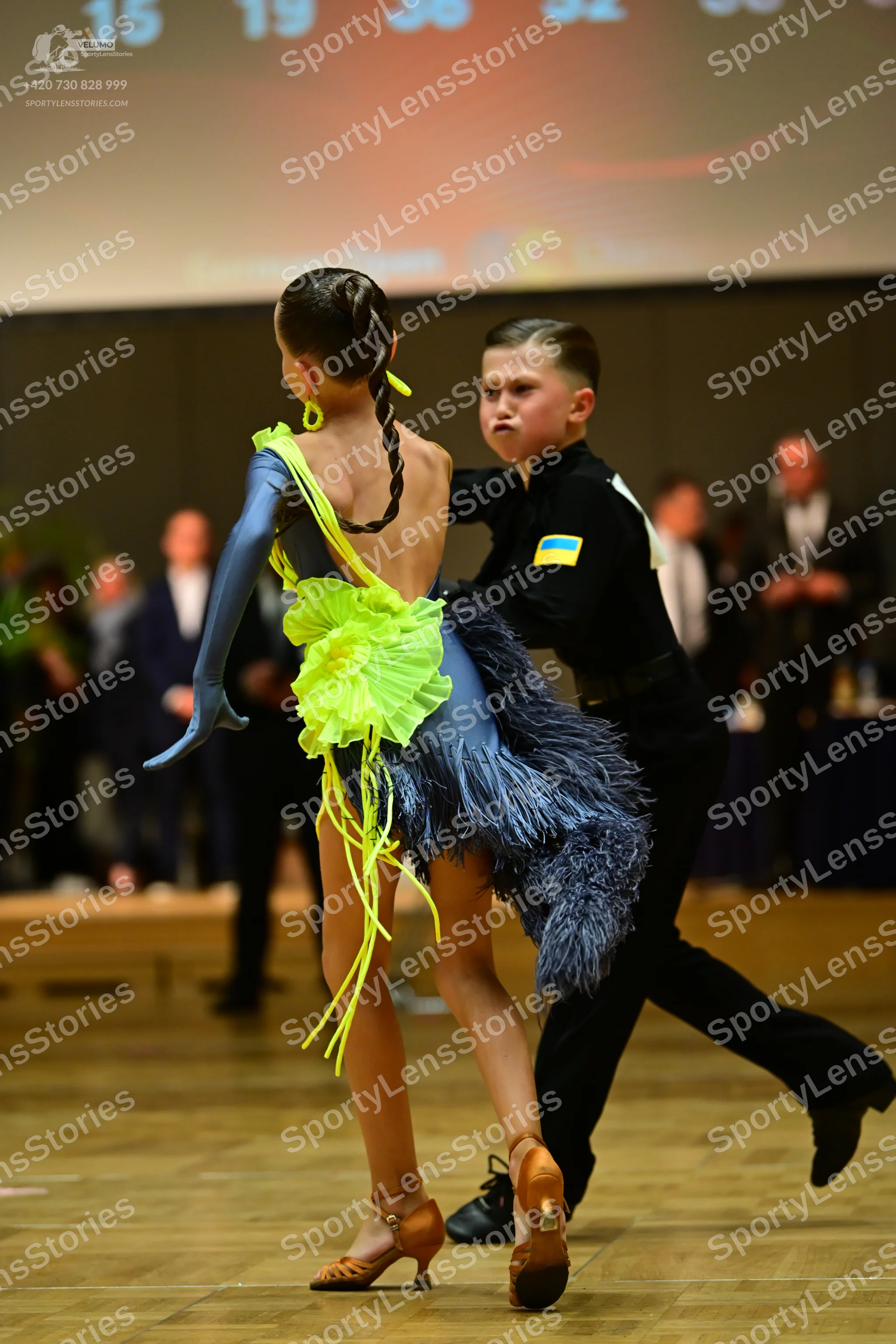 Dancesport competitor: Female dancer: blue and yellow latin dress with long blue sleeves, yellow fringe