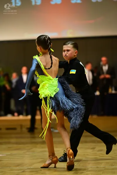 Dancesport competitor: Female dancer: blue and yellow latin dress with long blue sleeves, yellow fringe