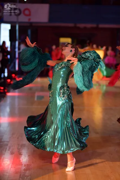 Dancesport competitor: Female dancer: emerald green ballroom dress with a shiny, metallic-looking fabri