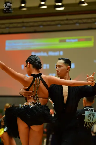 Dancesport competitor: Female dancer: black backless Latin dance costume with thin black straps, silver