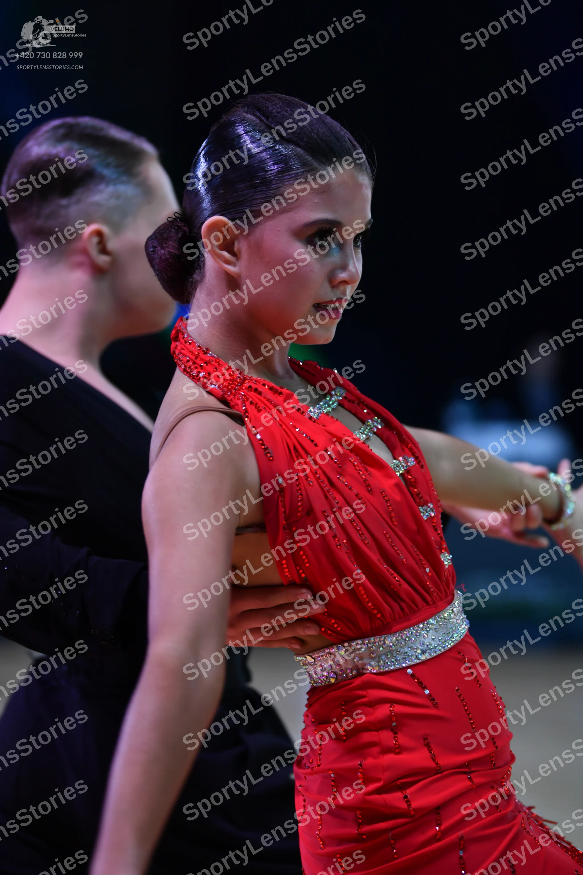 Dancesport competitor: Female dancer: red Latin dress with rhinestone embellishments around the necklin