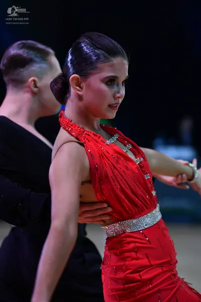Dancesport competitor: Female dancer: red Latin dress with rhinestone embellishments around the necklin
