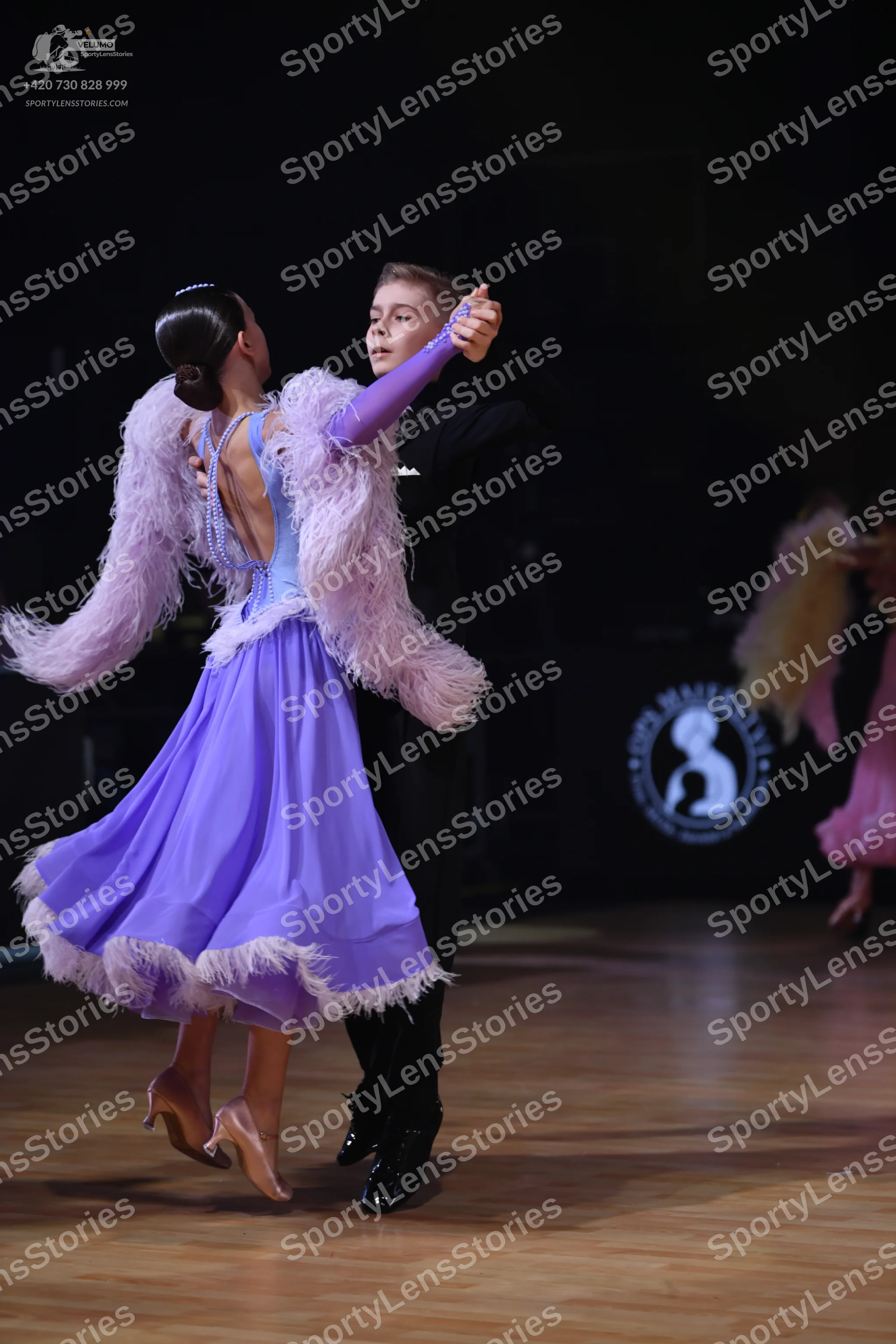 Dancesport competitor: Female dancer: lavender ballroom dress with a large, fluffy lilac feather boa ar
