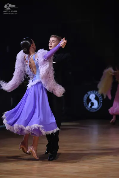 Dancesport competitor: Female dancer: lavender ballroom dress with a large, fluffy lilac feather boa ar