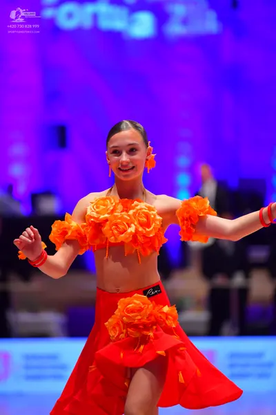 Dancesport competitor: Female dancer: orange and red latin dress featuring large orange fabric roses on