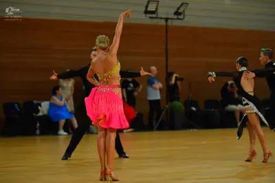 Dancesport competitor: Female dancer: gold sequined top and bright pink Latin skirt