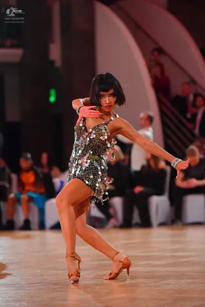 Dancesport competitor: Female dancer: short black Latin dance dress embellished with large, reflective 