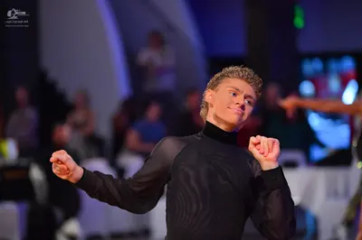 Dancesport competitor: Male dancer: black long-sleeved high-neck top with a subtle wavy pattern