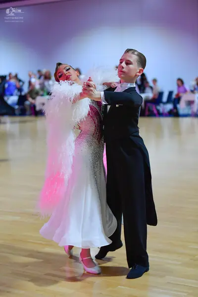 Dancesport competitor: Female dancer: white ballgown with voluminous white feather-like trim on the sho